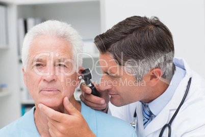 Doctor examining senior patients ear with otoscope