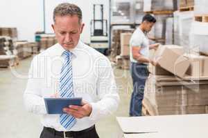 Boss using digital tablet in warehouse