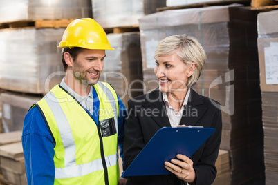 Warehouse manager showing clipboard to her colleague