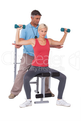 Trainer helping client lift weights