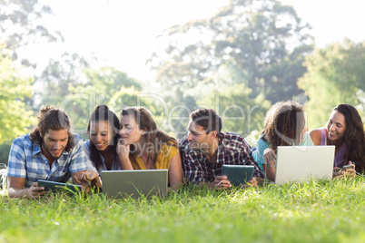 Smiling friends in the park using tablet pc and laptop