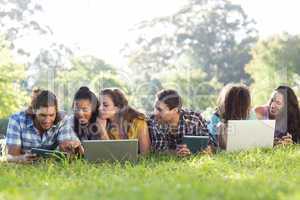 Smiling friends in the park using tablet pc and laptop