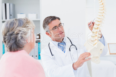 Doctor explaning anatomical spine to senior woman