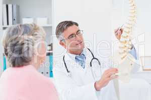 Doctor explaning anatomical spine to senior woman