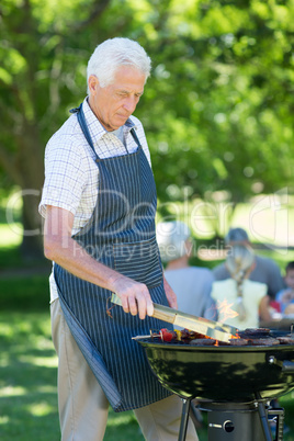 Concentrate grandfather doing barbecue