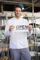 Portrait of a smiling baker holding open sign