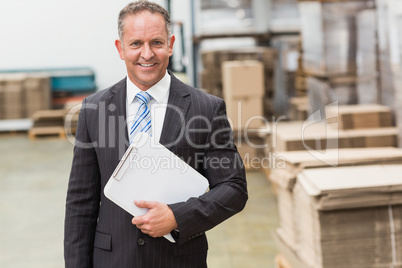 Portrait of a smiling boss holding clipboard