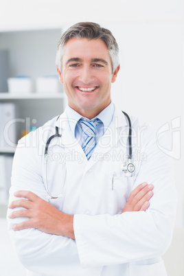 Confident doctor with arms crossed in clinic