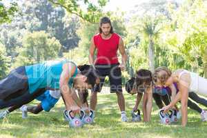 Fitness group planking in park with coach