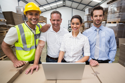 Warehouse managers and worker smiling at camera