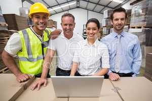 Warehouse managers and worker smiling at camera