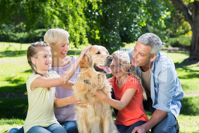 Happy family petting their dog in the park