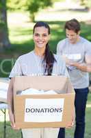 Happy volunteer brunette holding donation box