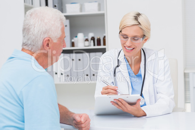 Doctor writing prescription for senior man