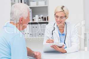 Doctor writing prescription for senior man