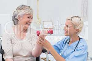 Nurse assisting senior patient in lifting dumbbell
