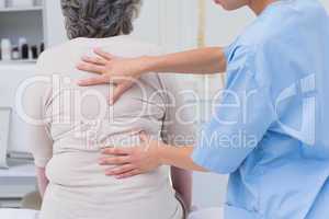 Nurse examining female patients back in clinic