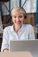 Smiling warehouse manager using laptop