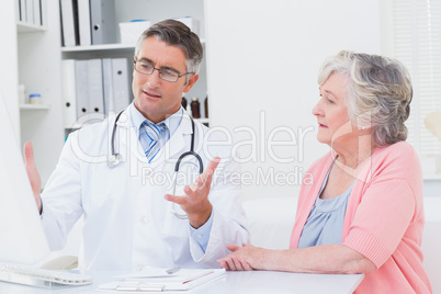 Doctor explaning reports to patient on computer