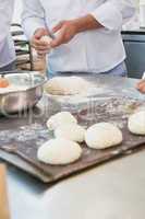 Colleagues putting dough on baking tray