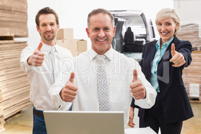 Warehouse team smiling at camera showing thumbs up