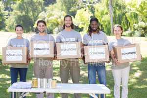 Happy volunteers with donation boxes in park