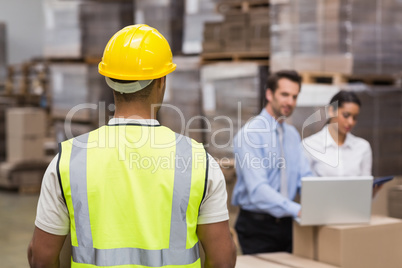Rear view of warehouse worker in front of his managers
