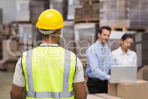 Rear view of warehouse worker in front of his managers