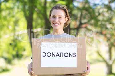 Happy volunteer in the park holding box