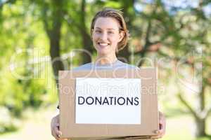 Happy volunteer in the park holding box