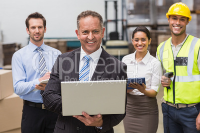 Smiling boss using laptop in front of his employees