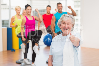 Happy senior woman gesturing thumbs up at gym