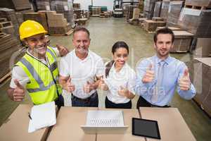 Warehouse team smiling at camera showing thumbs up