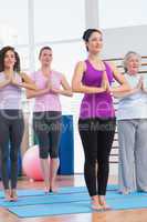 Female friends with hands clasped exercising in gym