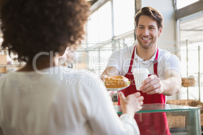 Smiling waiter giving lunch and hot drink to customer