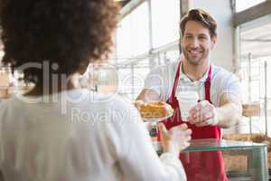 Smiling waiter giving lunch and hot drink to customer