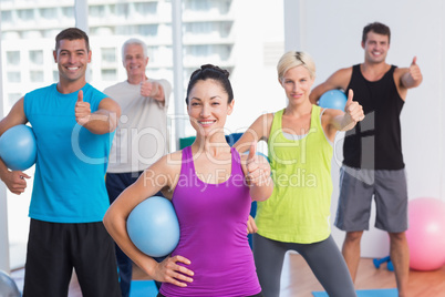 Instructor with class gesturing thumbs up at gym