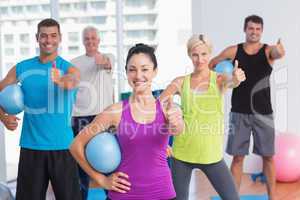 Instructor with class gesturing thumbs up at gym
