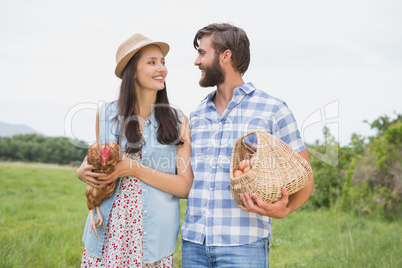 Happy farmers holding chicken and eggs