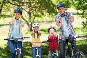 Happy family on their bike with thumbs up at the park