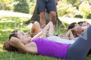 Fitness group doing sit ups in park with coach