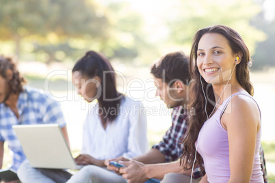 Smiling friends using media devices in park