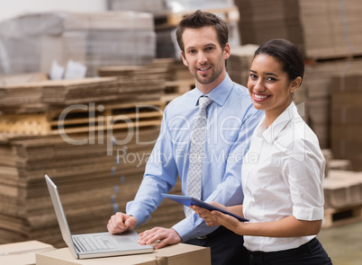 Managers working on laptop while smiling at camera