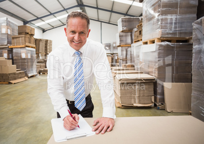 Smiling boss writing on clipboard