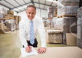 Smiling boss writing on clipboard