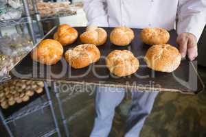 Mid section of chef showing tray of bread