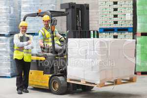 Driver operating forklift machine next to his manager