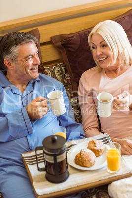 Happy mature couple having breakfast in bed