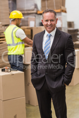 Smiling boss standing with hands in pockets