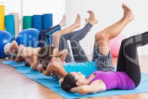 People practicing yoga on exercise mats at fitness studio